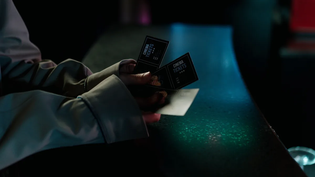 Mão segurando três ingressos de cinema à noite, em foco seletivo