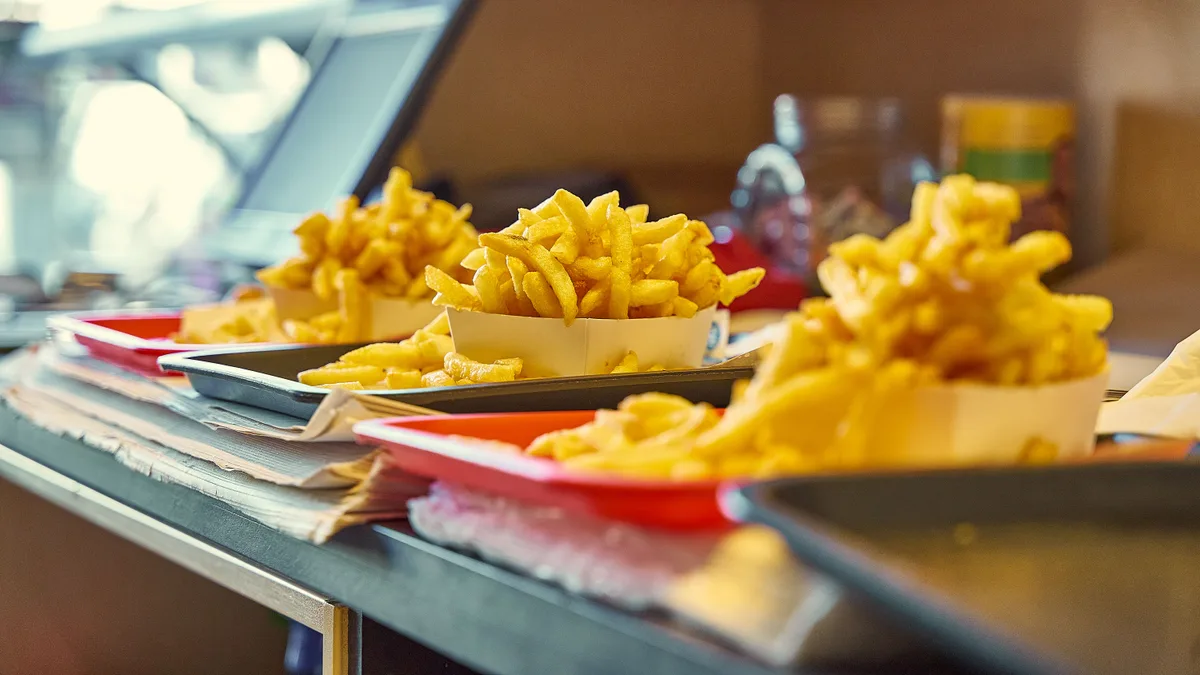 Batatas fritas servidas em bandejas vermelhas sobre o balcão de uma lanchonete