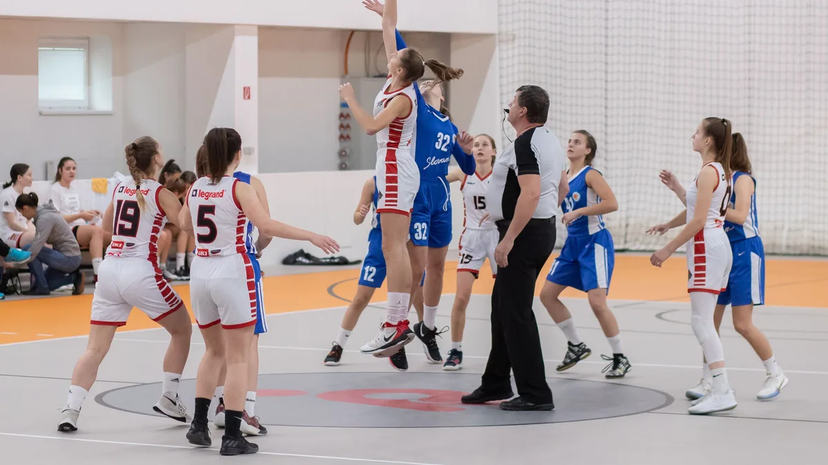 Jogadoras de basquete disputam a bola em quadra coberta durante partida