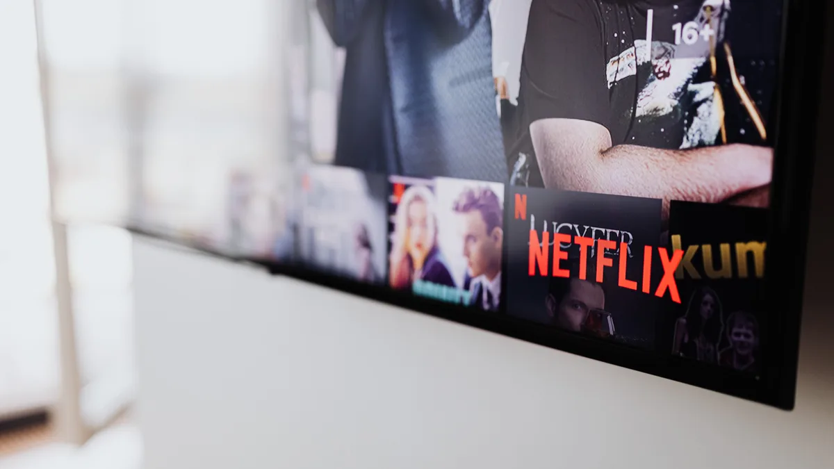 Homem comendo pipoca no sofá enquanto assiste a uma série na televisão