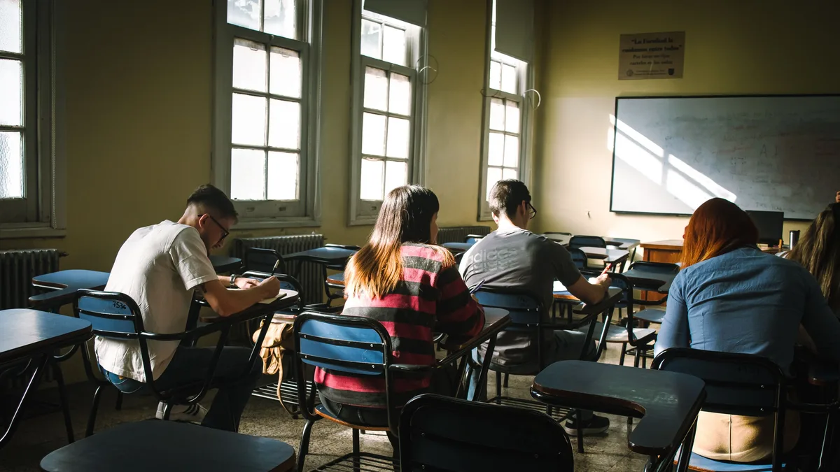Grupo de estudantes concentrados escrevendo em sala de aula iluminada
