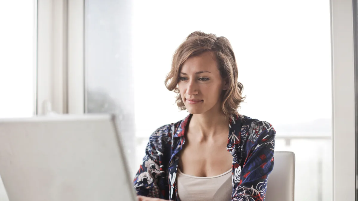 Mulher digitando em notebook em ambiente iluminado